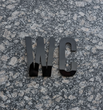 Minimalist sign, volumetric letters "WC" for toilet, gold-mirror